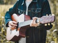 Handsome musician playing acoustic guitar at the grass field blur background. World music day. music and instrument concept Royalty Free Stock Photo