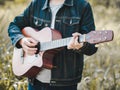 Handsome musician playing acoustic guitar at the grass field blur background. World music day. music and instrument concept Royalty Free Stock Photo