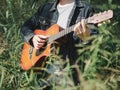 Handsome musician playing acoustic guitar at the grass field blur background. World music day. music and instrument concept Royalty Free Stock Photo