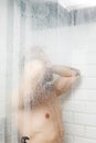 Handsome naked young man taking shower in bathroom