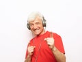 Handsome old man in casual wear and headphones is listening to music and show ok sign on white background Royalty Free Stock Photo