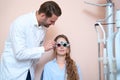 Handsome optometrist is examining eyesight of woman patient in optician office