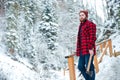 Handsome pensive man with axe standing in mountain winter forest