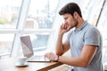 Handsome pensive man working with laptop while having coffee break Royalty Free Stock Photo