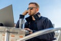 Handsome pensive stylish man sitting on balcony and working on laptop Royalty Free Stock Photo