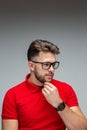 Handsome pensive young male businessman in glasses touching chin thinking, studio portrait on gray with copy space Royalty Free Stock Photo