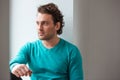 Handsome pensive young man sitting and looking at the window