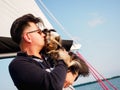 Handsome person hugs his small dog yorkshire terrier on a sailing yacht during vacations, travel with pets concept