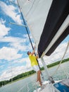 Handsome person raise the sail on a sailing yacht, summer vacations on sailboat