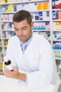 Handsome pharmacist lokking at medicines bottle