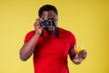 Handsome photographer happy young african man Kenya Africa tourist isolated yellow wall background holding tickets with