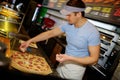 Handsome pizzaiolo making pizza at kitchen in pizzeria.