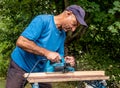 Handsome planing wooden plank with a electric plane Royalty Free Stock Photo