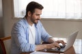 Handsome pleasant young man working remotely on computer at home. Royalty Free Stock Photo