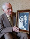 Handsome 80 plus year old senior man holding his wedding photograph. Love forever concept Royalty Free Stock Photo