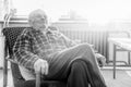 Handsome 80 plus year old senior man portrait. Black and white full body image of elderly man sitting in an armchair.