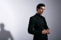 Portrait of a brutal young man with hairstyle, in black suit, looking at camera, in studio, over white background. Royalty Free Stock Photo