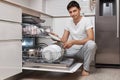 handsome positive man putting plates in dishwasher machine Royalty Free Stock Photo