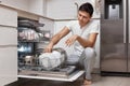 handsome positive man putting plates in dishwasher machine Royalty Free Stock Photo