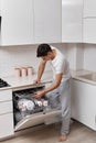 handsome positive man putting plates in dishwasher machine Royalty Free Stock Photo