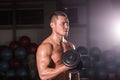 Handsome power athletic guy bodybuilder doing exercises with dumbbell. Fitness muscular body on dark background Royalty Free Stock Photo