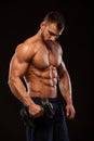 Handsome power athletic man with dumbbell is confidently looking forward. Strong bodybuilder with six pack, perfect abs Royalty Free Stock Photo