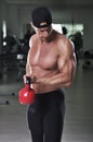 Handsome powerful athletic man doing biceps exercise with kettle bell