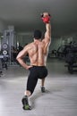 Handsome powerful athletic man doing complex exercise with kettle bell