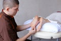 Handsome practicing masseur kneads feet of female client, who li