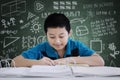 Handsome preteen boy writing in the classroom