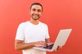 Handsome programmer man with laptop on red background