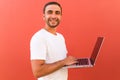 Handsome programmer man with laptop on red background