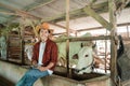 handsome rancher wearing a cowboy hat sitting in a cage holding a digital tablet