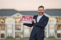 Handsome real estate agent holding banner house for sale. House with land and insurance. Man real estate agent in Royalty Free Stock Photo