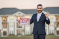 Handsome real estate agent holding banner house for sale. House with land and insurance. Man real estate agent in Royalty Free Stock Photo