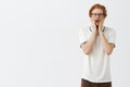 Handsome redhead male computer geek with beard in glasses and casual polo shirt holding hands on face and gazing with Royalty Free Stock Photo