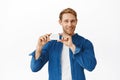 Handsome redhead man showing his credit card and smiling pleased, bank advertisement, shopping or special discounts Royalty Free Stock Photo