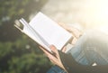 Handsome redhead young woman sitting on a small wall and reading a book with city in the background - Concept Relaxing in nature