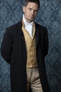 A handsome Regency gentleman wearing a gold waistcoat, breeches, and a black coat