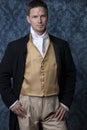 A handsome Regency gentleman wearing a gold waistcoat, breeches, and a black coat