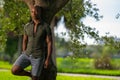 Handsome relaxed man leaning on tree in the park. African American model wearing a tight shirt showing off muscles Royalty Free Stock Photo