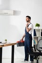 Handsome repairman standing with toolbox near