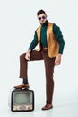 handsome retro styled man putting leg on vintage television