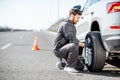 Worker changing car wheel on the highway Royalty Free Stock Photo