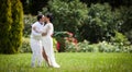 Handsome, romantic groom kissing newly happy bride in park