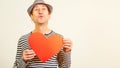 Handsome romantic guy is making airkiss. Happy Valentines Day. Funny man holding a red paper heart, on white background. Cope