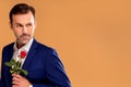 Handsome romantic man in suit holding one red rose in hand. Elegant look. Date. Real people lifestyle