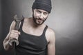Handsome rough man holding a wrench over a textured grey background Royalty Free Stock Photo
