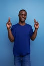 handsome 25s african guy in casual blue t-shirt crossed his fingers