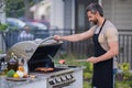 Handsome 40s man preparing barbecue. Male cook cooking meat on barbecue grill. Guy cooking meat on barbecue for summer Royalty Free Stock Photo